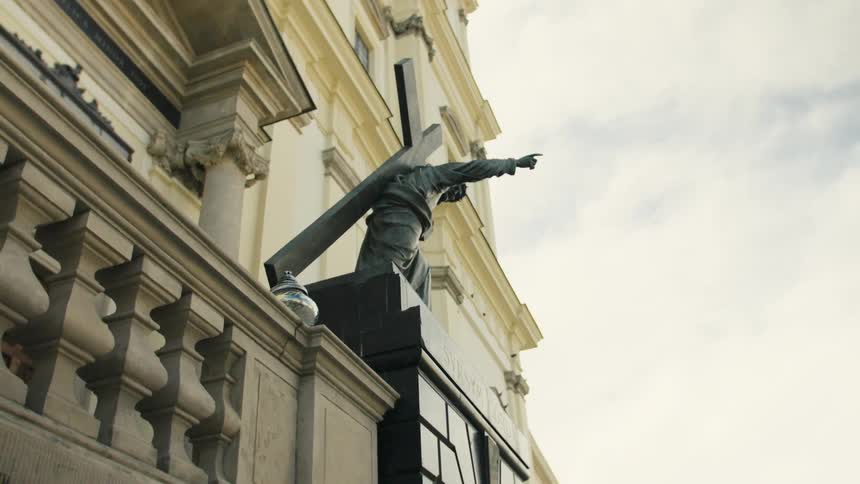 Stone robed figure holding a cross adorns the old buildings facade