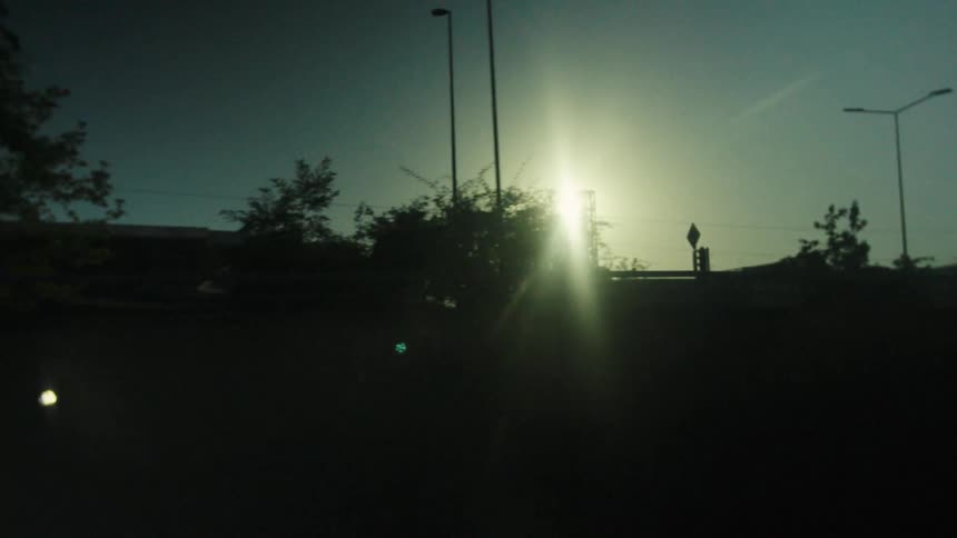 Bright sun shines over urban structures at sunset
