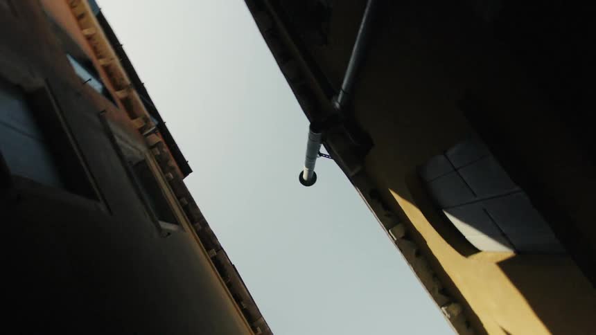 A dizzying upward view between tall buildings while moving in circular motion