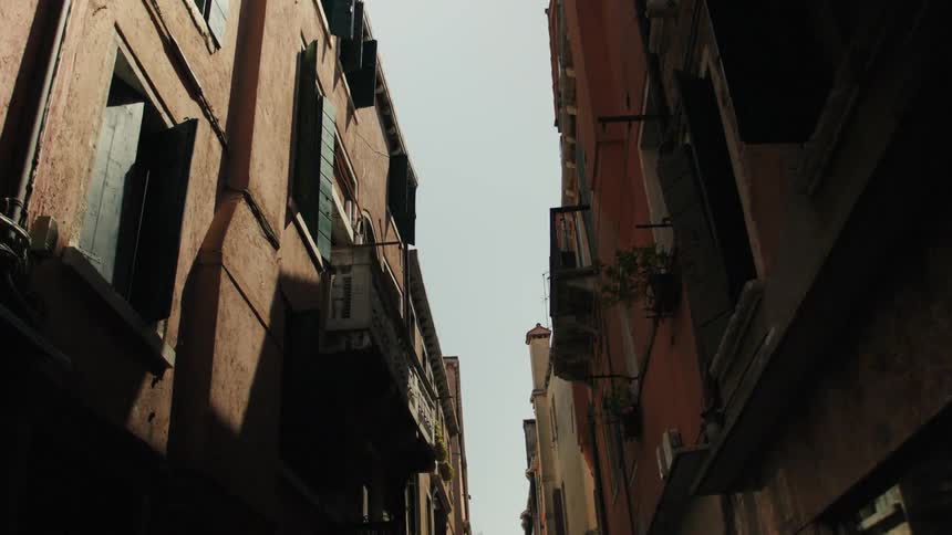 Narrow streets flanked by old buildings with open wooden shutters under a clear sky