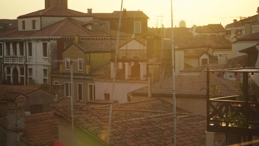 Goldenhour light spills over terracotta rooftops chimneys and balconies across a dense neighborhood