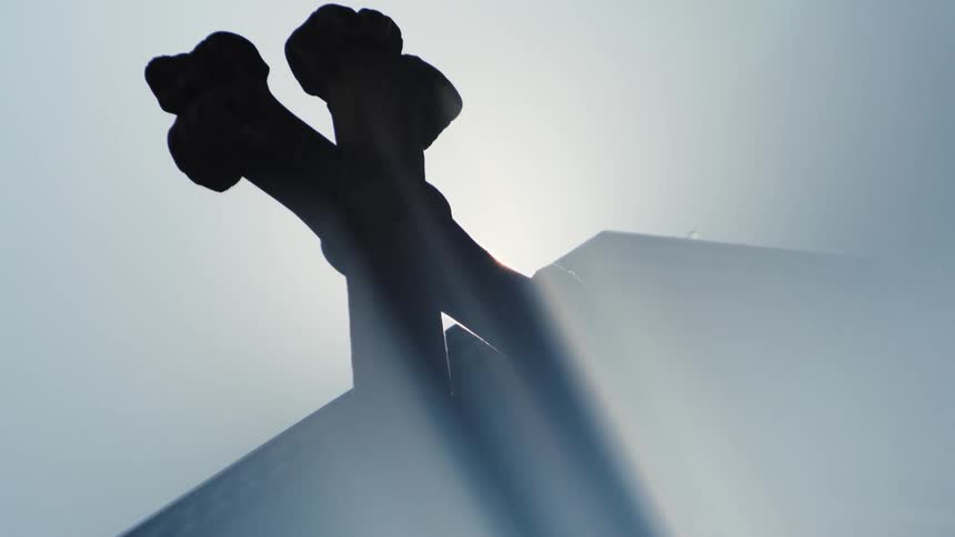 Sunlight reflects off a cross atop a church building