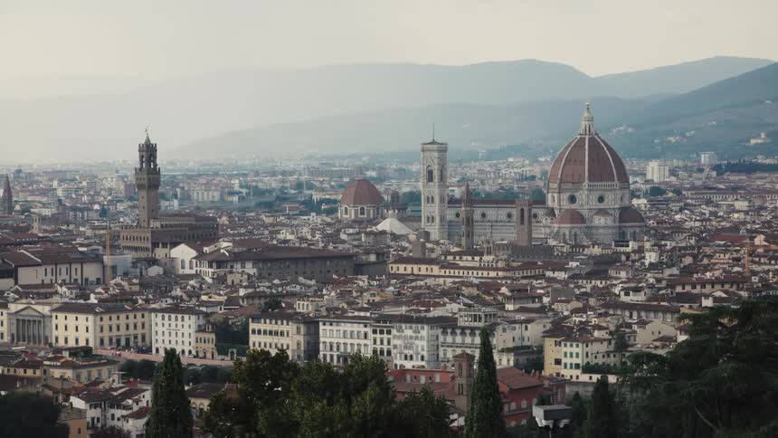 The video provides a stunning panoramic view of the city of florence italy dominated by the iconic duomo florence cathedral and its massive dome and bell tower the cityscape is dense with terracotta rooftops and historical buildings set agai