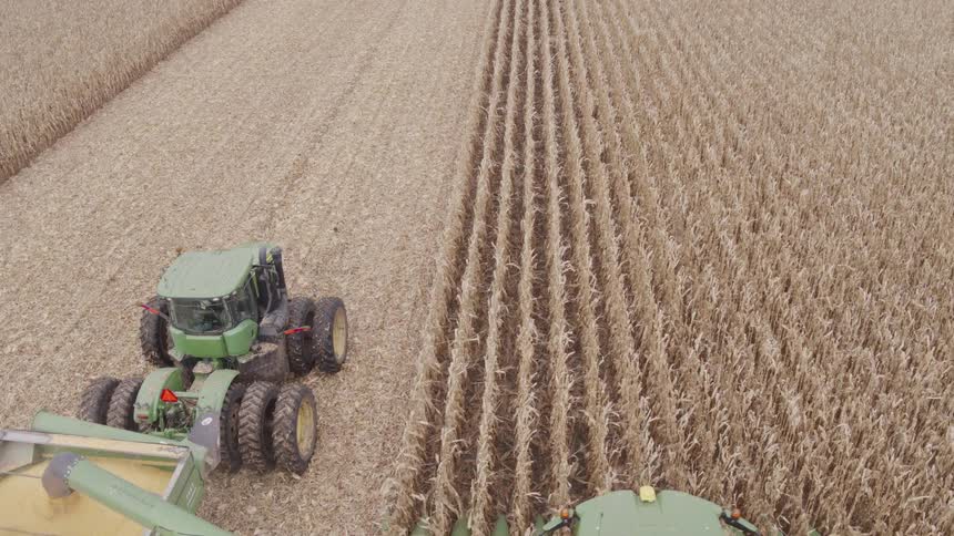 Harvester transferring grains into a trailer amid the crop field