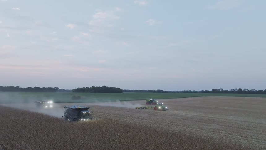 The farm vehicles work the field together