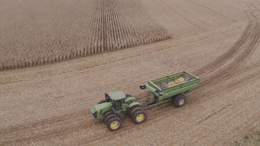 The tractor pulls a trailer across the farm
