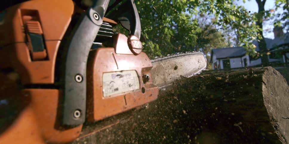 Husqvarna chainsaw positioned on a tree trunk in an outdoor setting