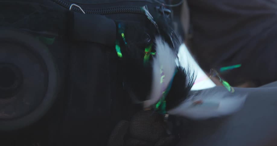 The short video shows a closeup of something black possibly a bag or fabric with what appears to be small frayed pieces of iridescent or brightly colored plastic thread or fiber attached to or stuck in the materialthese pieces flash with colo
