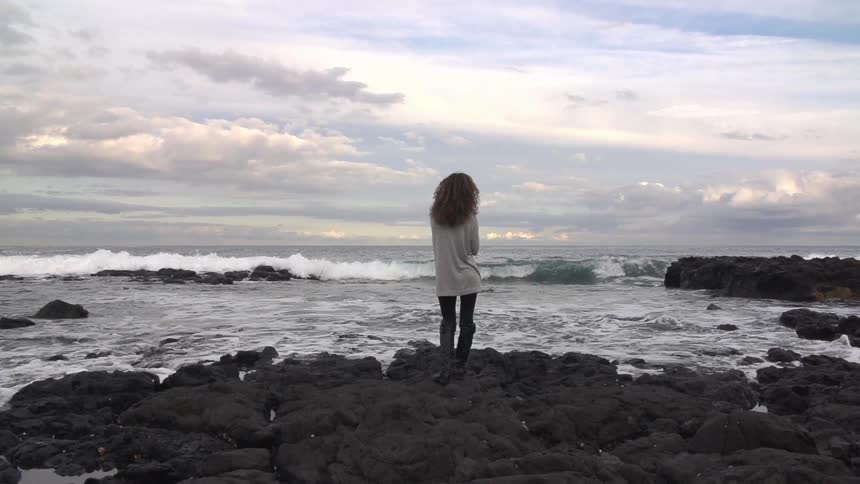 Woman standing on some rocks by the coast