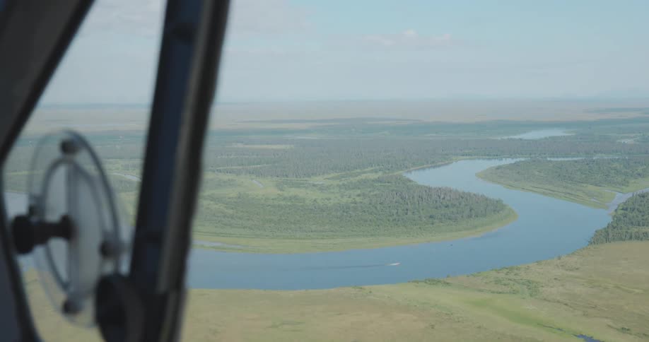 Landscape with a winding river seen through an airplane window at low altitude
