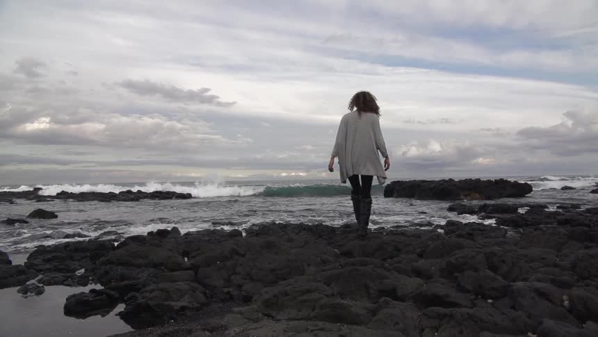 Woman walking on a rocky beach