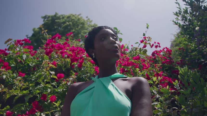 The woman is standing in front of red flowers