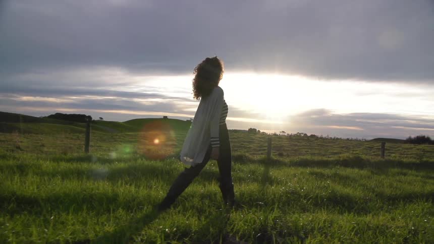 A woman walking across a field on a cloudy day