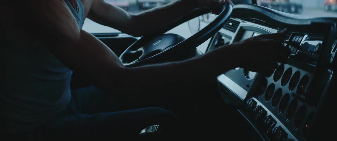 Man sitting inside of a truck flipping switches on the panel