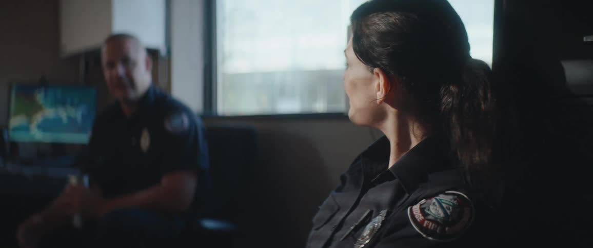 Two firefighters talking in a room lit by natural light coming through the window
