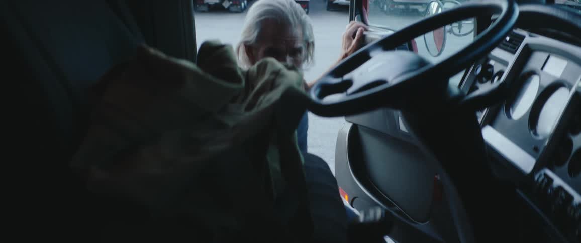 A man puts a bag in an industrial truck and gets in the drivers seat