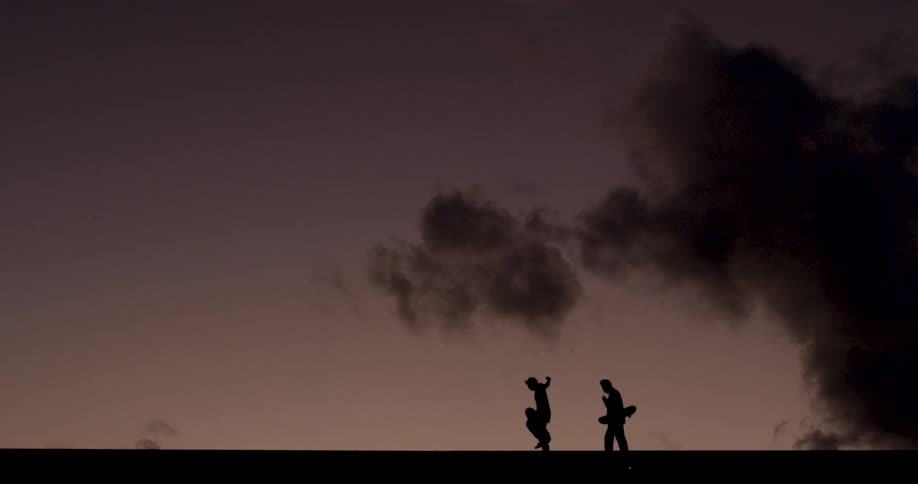 Two people walking under a purple sky with dark clouds in the background