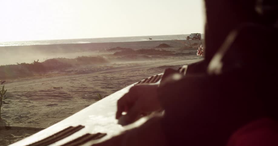 Person handling objects on a surface near the beach at sunset