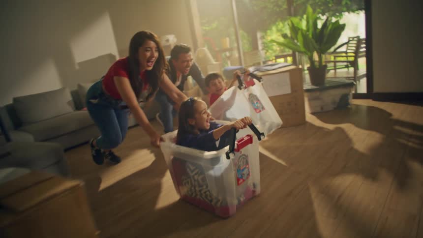 Parents push their children in bins across the room