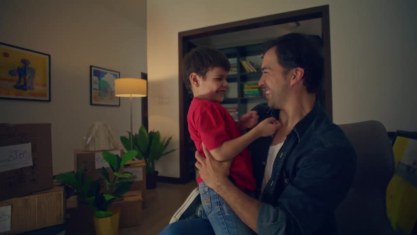 Father holding his son in his arms as they both smile indoors