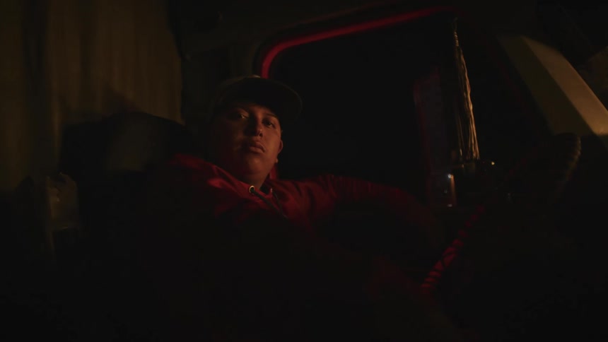 Man sitting inside a truck at night illuminated by a warm yellow light