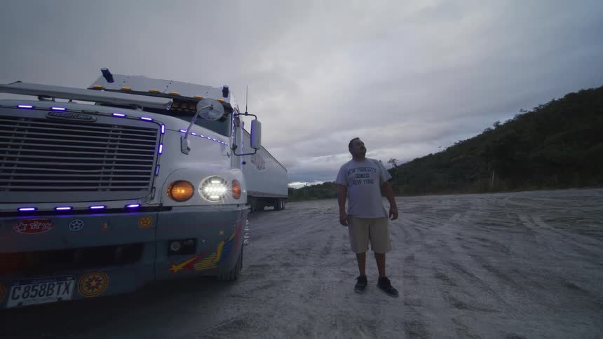 Man standing beside a litup truck parked on a dirt road