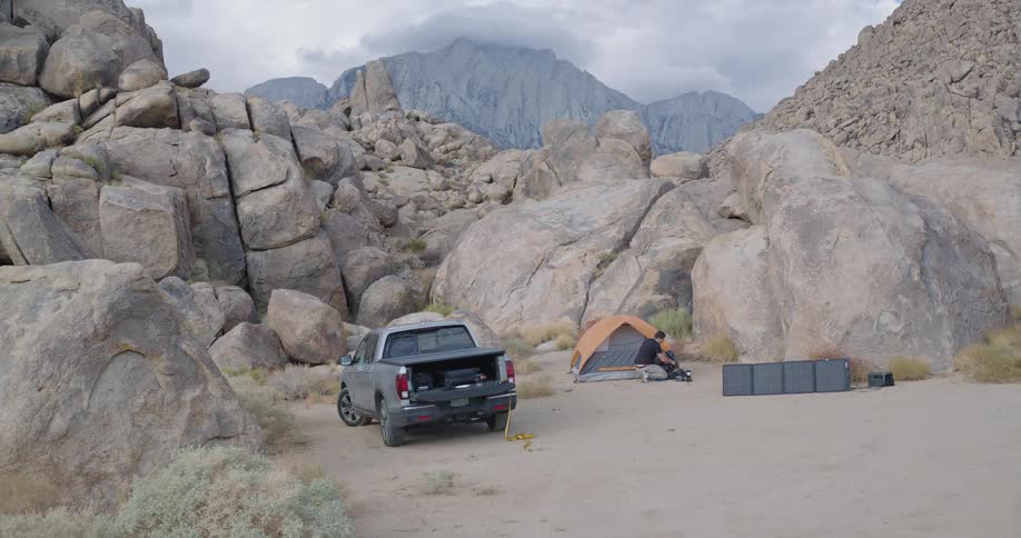 Man moves around a campsite locate near a tor in a boulder field in mountainous terrain