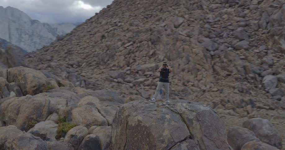 The hiker is using binoculars near the mountain range