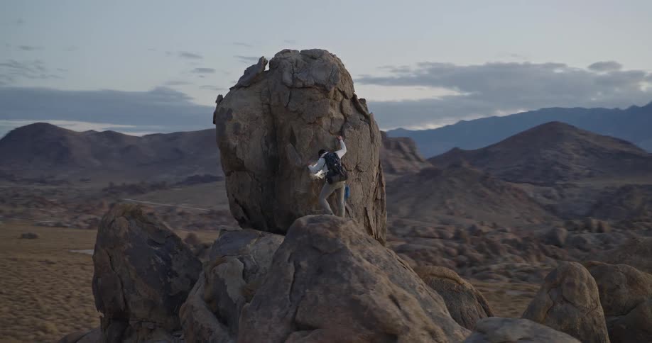 The man climbs down from the large boulder