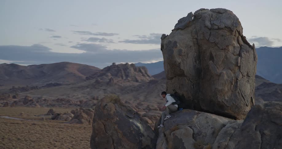 Man standing on rock with headlamp in mountainous region at dawn