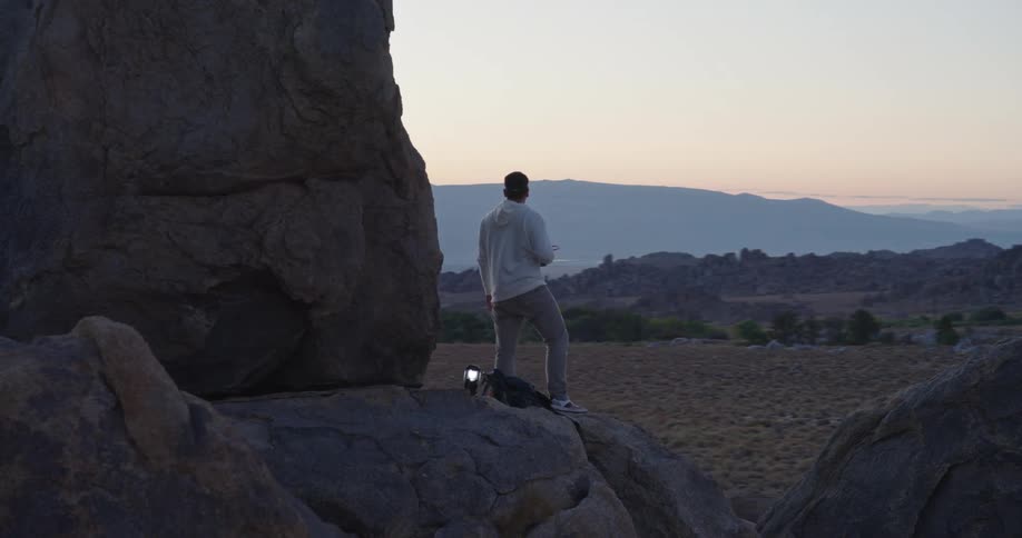 The man is perched on the boulder overlooking the badlands