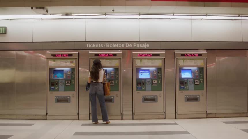 Woman in front of ticket machines at metro station with bilingual signage
