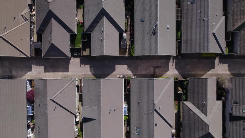 An aerial top down shot slowly pans over the rooftops of a residential neighborhood