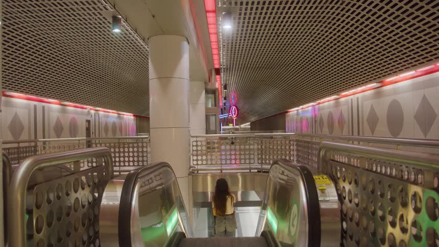 Woman wearing a baseball cap going down the escalator in a building