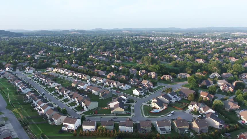 Homes arranged along winding streets surrounded by greenery and dense forest