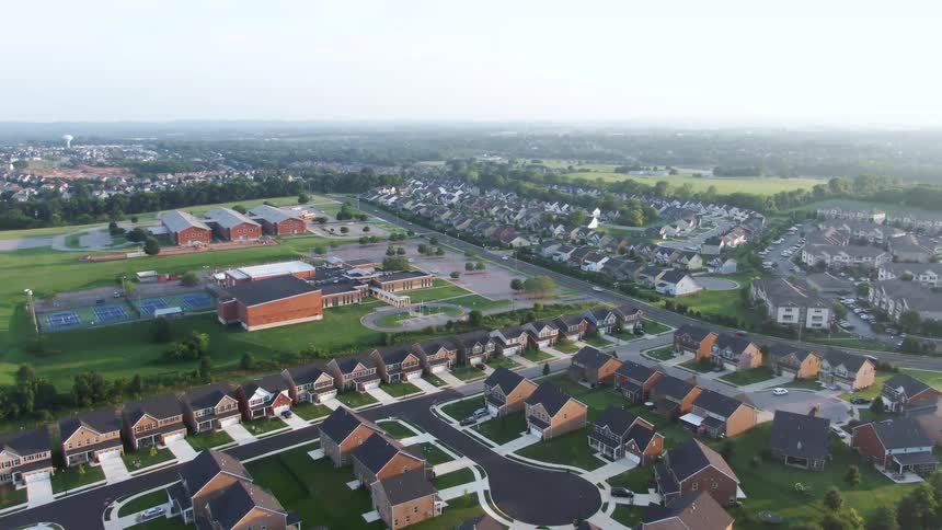 Aerial view of suburban neighborhood with school at the center surrounded by organized homes and green areas in a semirural setting