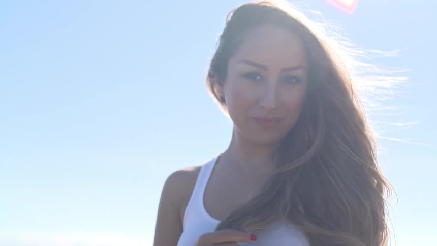 Woman with flirty smile standing with hair blowing in the wind