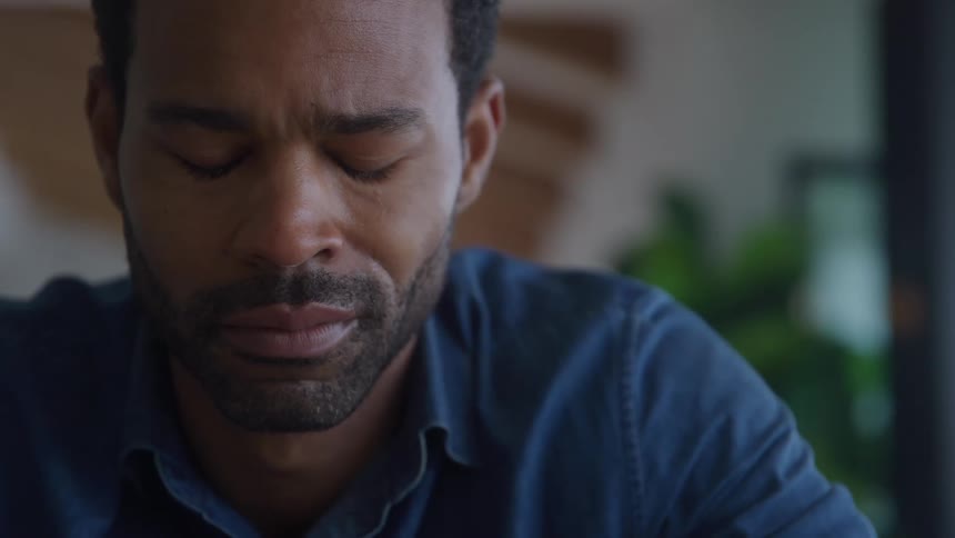 Closeup short of a man crying with pained expression sitting indoors