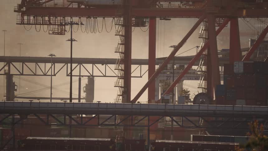 Metal structures and cranes operating in shipping yard with containers