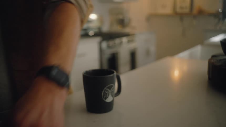 Person places a cup on the counter and picks up a lunchbox and key