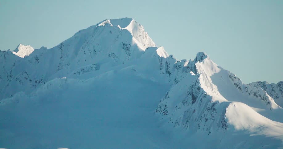 The sunlight reflects on the snow covered mountains