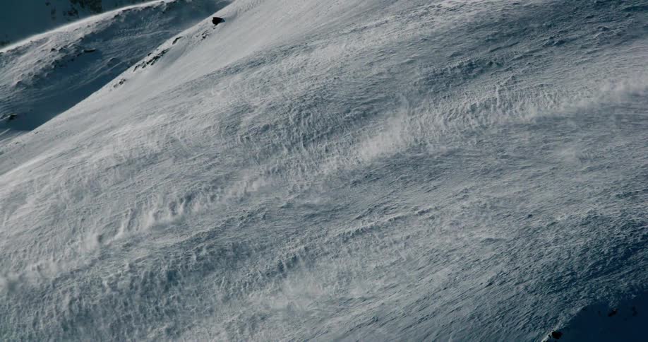 The wind creates a wave of snow on the slope