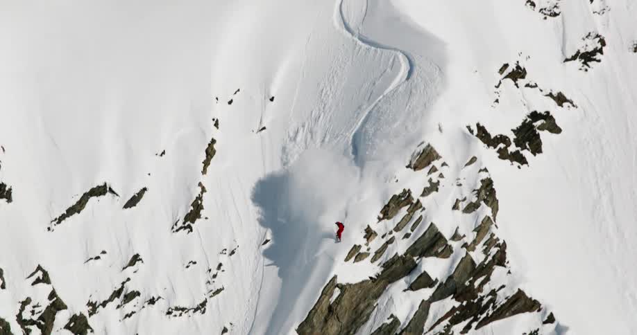 A person snowboarding down a mountain slope in an arctic region during daytime