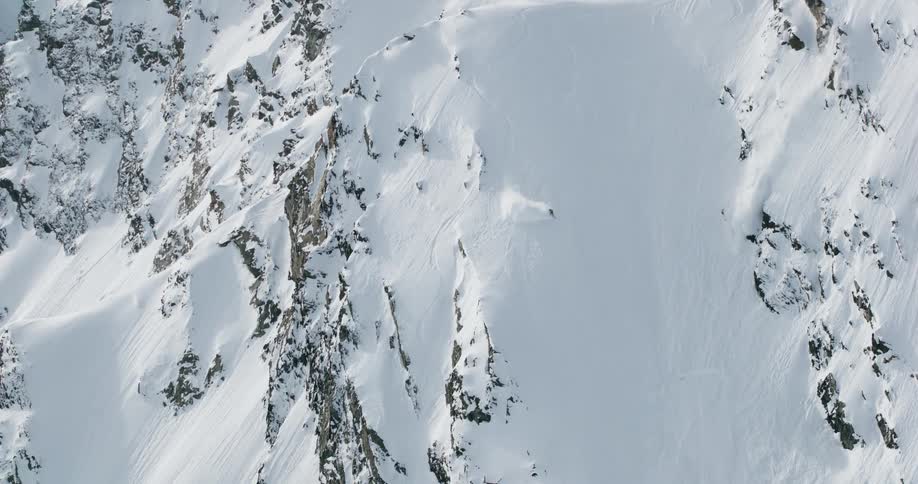 The person skis down the steep mountain side