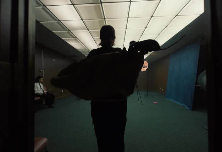 Person walks toward a blue backdrop in a room with bright lighting and studio equipment