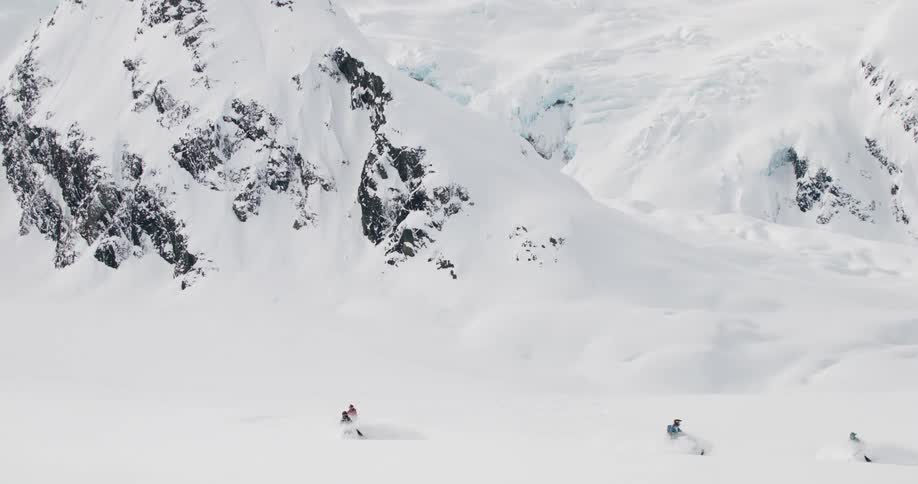 People are driving their snowmobiles around by the mountain