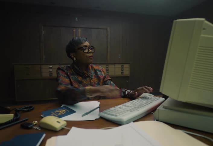 A black middle aged woman using a retro computer while working in an office