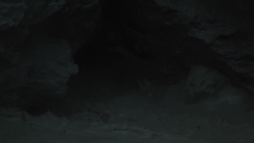 Black mud splashes and bubbles inside a dark rocky cave