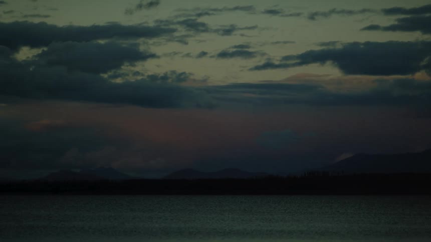 Heavy clouds are over the mountains past the lake