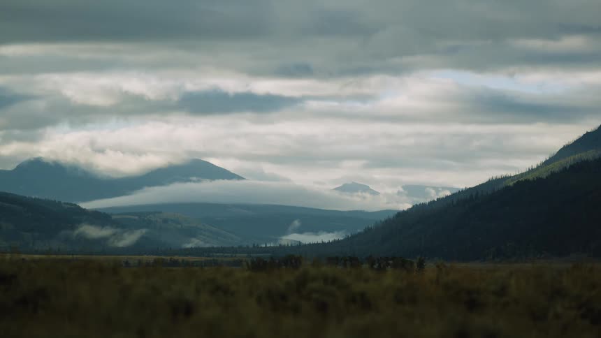 Layers of mistcovered mountains stretch beneath a cloudy sky